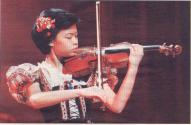 [Vanessa playing violin in puff-sleeved blouse, flower in hair, prob. at a younger age]