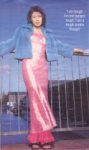 [Vanessa in full-length shiny pink dress, sandals and sky-blue jacket]