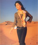 [Vanessa walking in desert, wearing black jeans and brown jacket-like top]