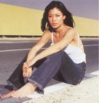 [Vanessa sitting barefoot at side of a road, in black jeans and white top]